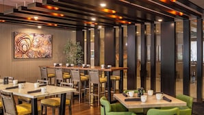 A modern dining area with wooden tables and chairs, a large abstract painting on the wall, and a plant in the corner. - DoubleTree by Hilton Hotel San Bernardino (San Bernardino)