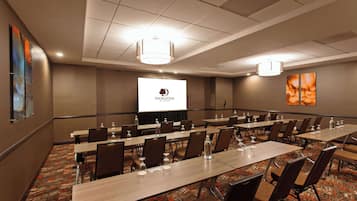 A conference room with long tables, chairs, and a projector screen displaying the DoubleTree logo.