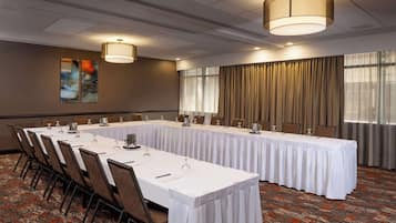 Un salón de conferencias con una larga mesa, sillas y un amplio ventanal con cortinas.