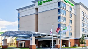 Holiday Inn -hotelli, jossa on selkeä sisäänkäynti, useita lippuja ja katettu pysäköintialue.