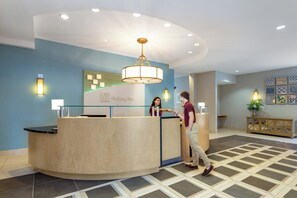 A reception area with a curved reception desk, a chandelier, and a wall-mounted sign that reads 'Holiday Inn.'