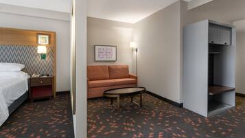 A hotel room with a bed, a nightstand, a sofa, a small table, and a wardrobe.