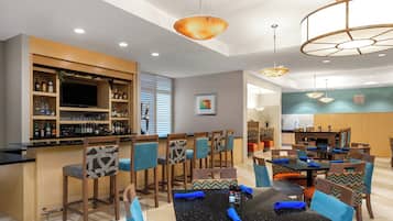 A restaurant with a bar area, multiple dining tables, and chairs with patterned cushions.