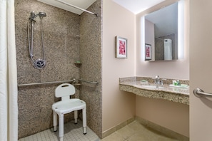 A bathroom with a shower, a toilet, a sink, and a mirror.