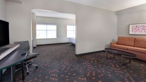 Ein Hotelzimmer mit Schreibtisch, Stuhl, Sofa und einem großen Fenster.
