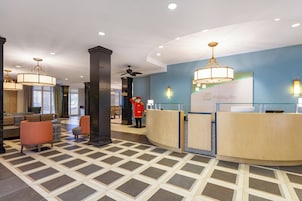 Un hall de hotel con mostrador de recepción, zona de estar y un pilar grande.