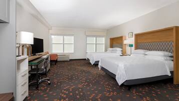Une chambre d’hôtel avec deux lits, un bureau avec un ordinateur, une chaise et un téléviseur.