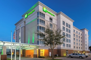 Um hotel Holiday Inn com fachada moderna, várias janelas e céu claro.