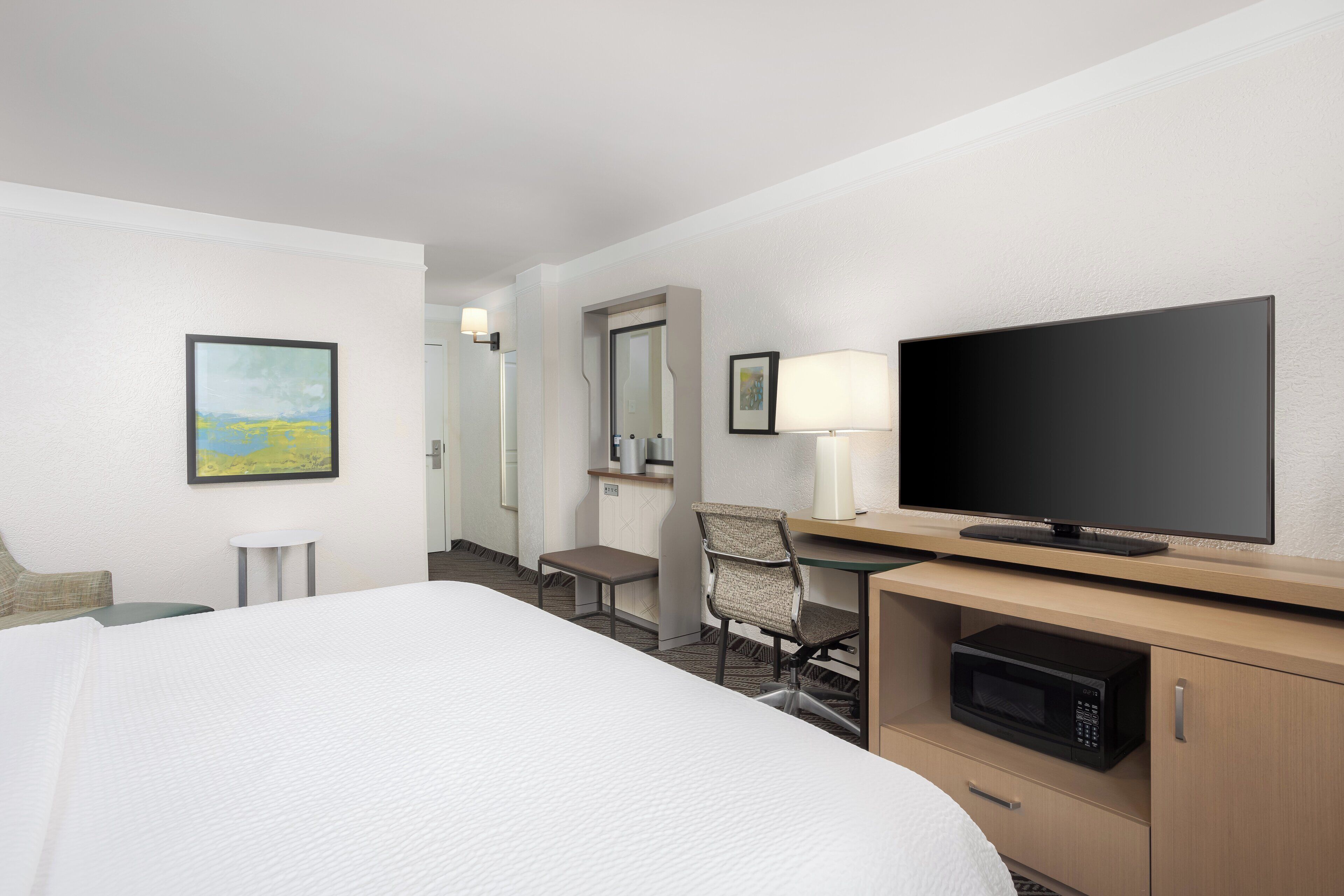 Une chambre d’hôtel comprenant un lit, un bureau avec une télévision, un four à micro-ondes et une chaise.