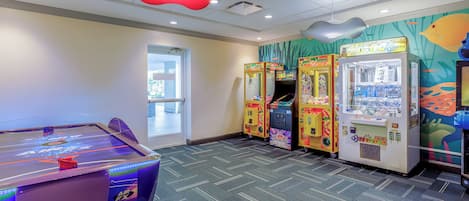 A room with a pool table, arcade machines, and a mural of fish.