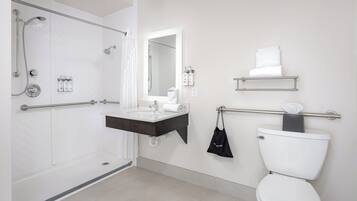 A modern bathroom with a walk-in shower, a vanity with a mirror, a toilet, and a towel rack.