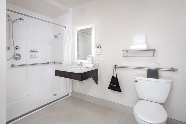 A modern bathroom with a walk-in shower, a vanity with a mirror, a toilet, and a towel rack.