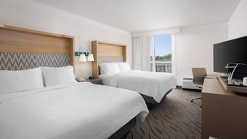 Une chambre d’hôtel avec deux lits, un bureau, une télévision et une fenêtre donnant sur un paysage agréable.