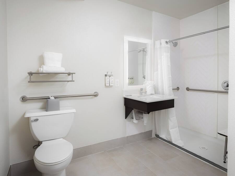 Un baño moderno con inodoro, lavamanos, ducha con puerta de cristal y barra para toallas.
