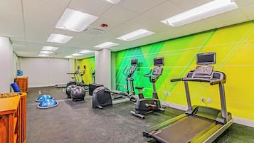 Une salle de sport équipée de tapis de course, de vélos d’appartement et de ballons d’exercice.