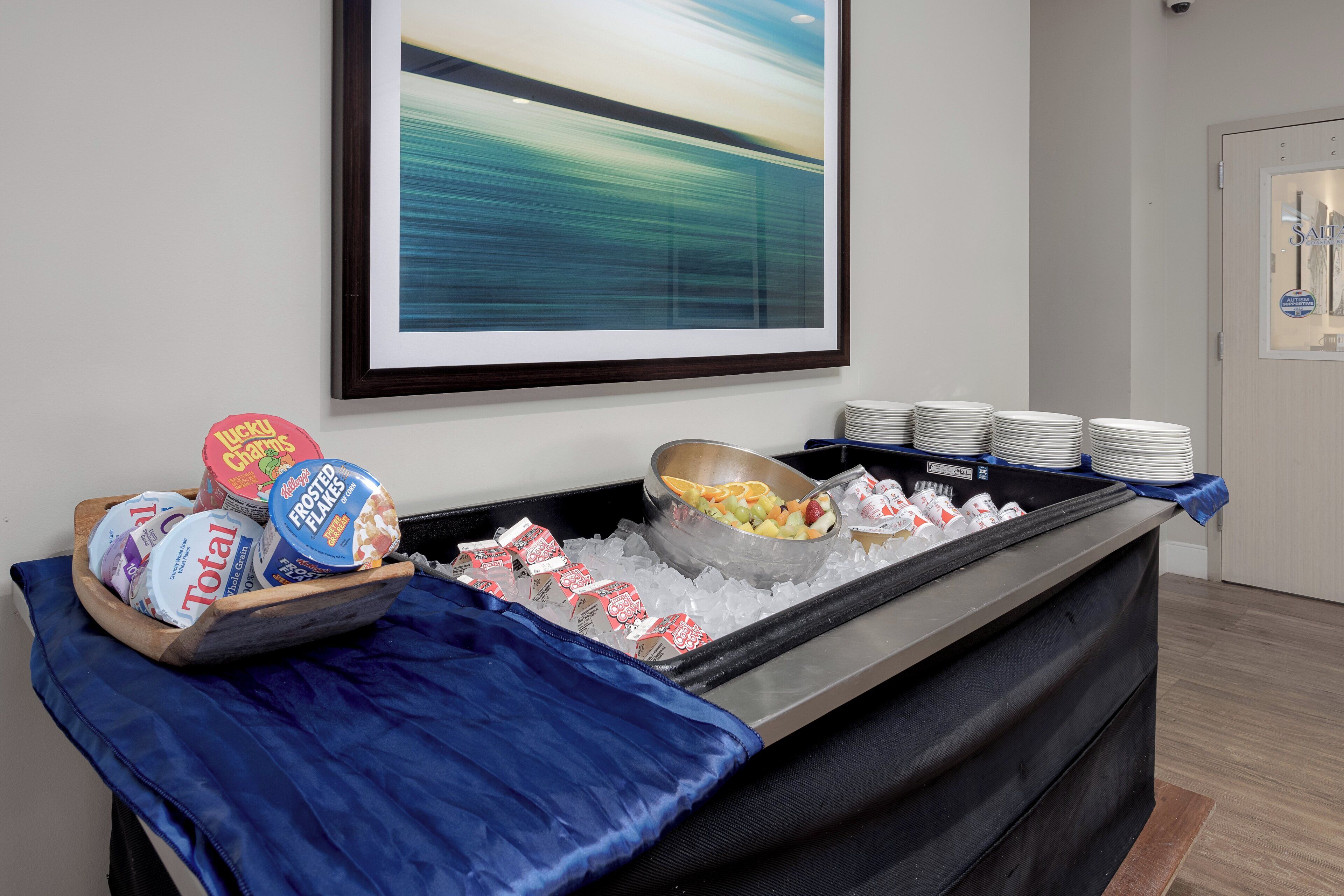 A buffet setup with various food items and a large abstract painting on the wall.
