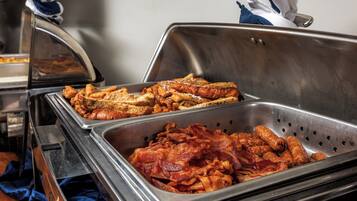 Un buffet proposant une variété de plats, notamment du bacon et des sandwichs.