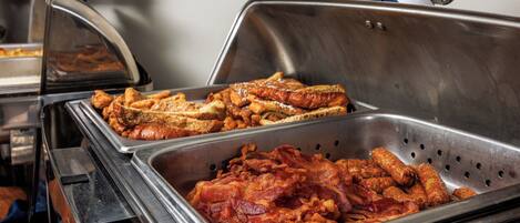 A buffet with various food items including bacon and sandwiches.