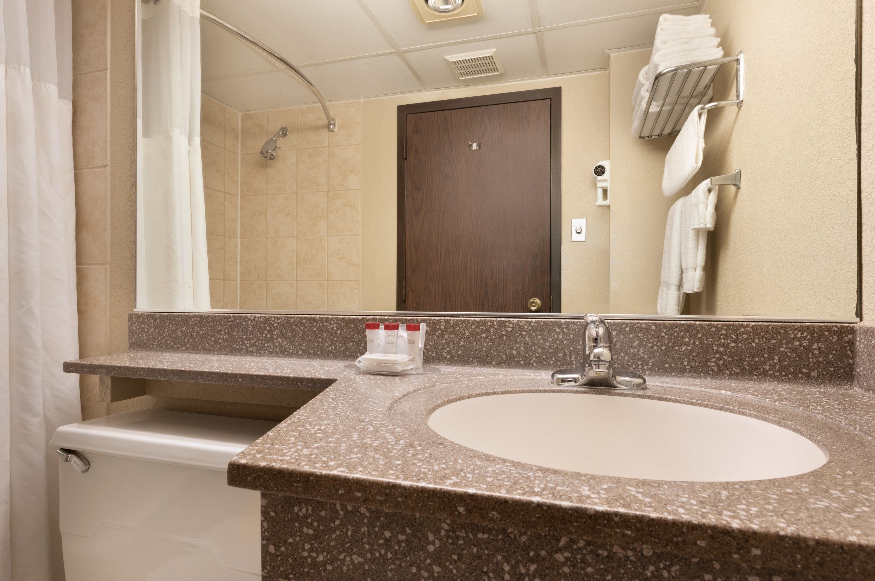 A bathroom with a sink, mirror, shower, and towel rack.