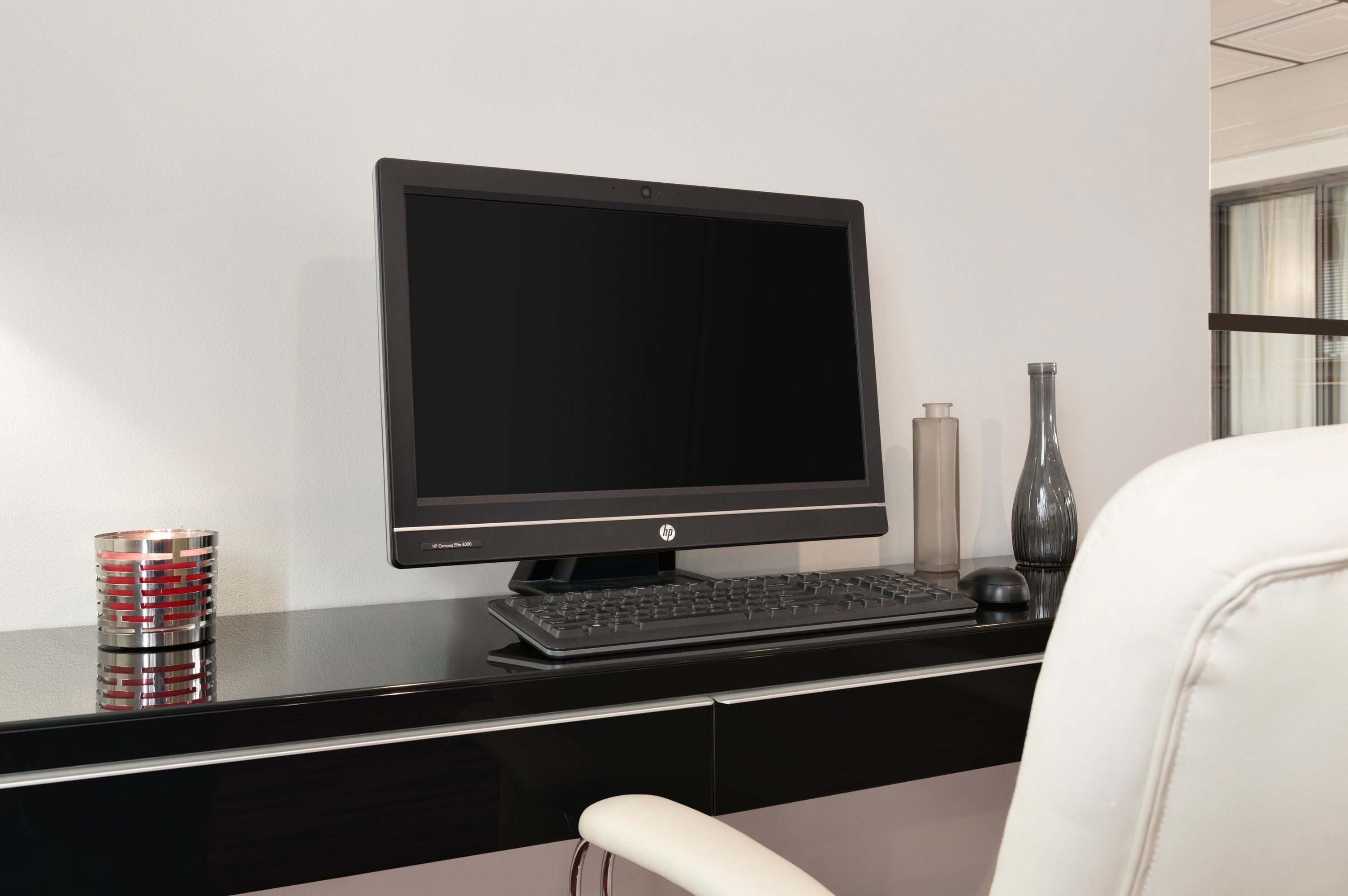 A modern office desk with a HP monitor, keyboard, and mouse.