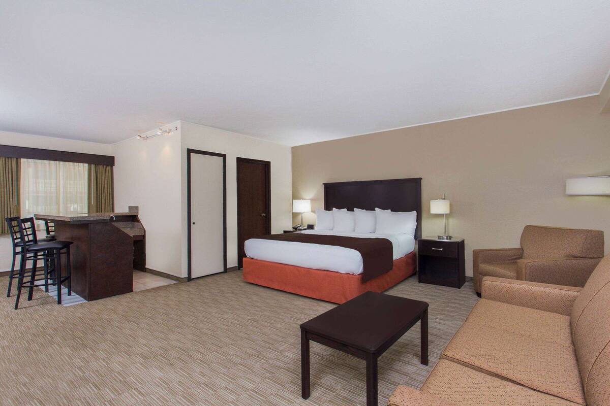 Ein Hotelzimmer mit einem Bett, einem Schreibtisch mit Stühlen, einer Couch und einem kleinen Tisch.