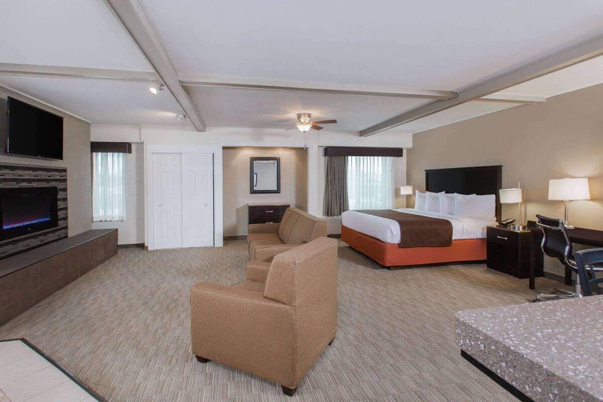 Ein Hotelzimmer mit Bett, einer Couch, einem Schreibtisch, einem Fernseher und einem Deckenventilator.