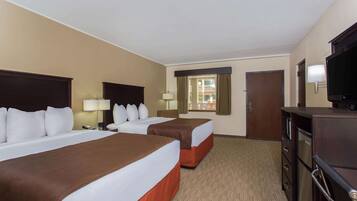 Habitación de hotel con dos camas, un televisor, un escritorio y vistas al exterior.