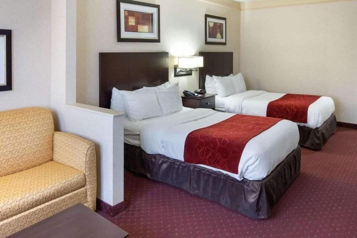A hotel room with two beds, a chair, and two framed pictures on the wall.