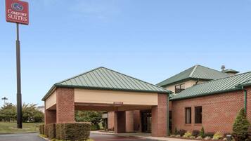 A Comfort Suites hotel with a brick facade, green metal roofing, and a covered entrance.