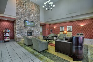 Un vestíbulo con pared de piedra, chimenea y zona de estar con sofás y una mesa de centro.