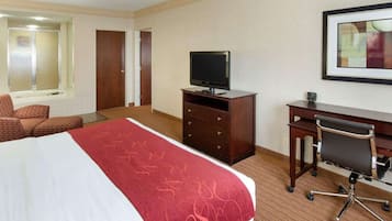 A hotel room with a bed, a desk, a chair, a television, and a bathroom with a shower and toilet.