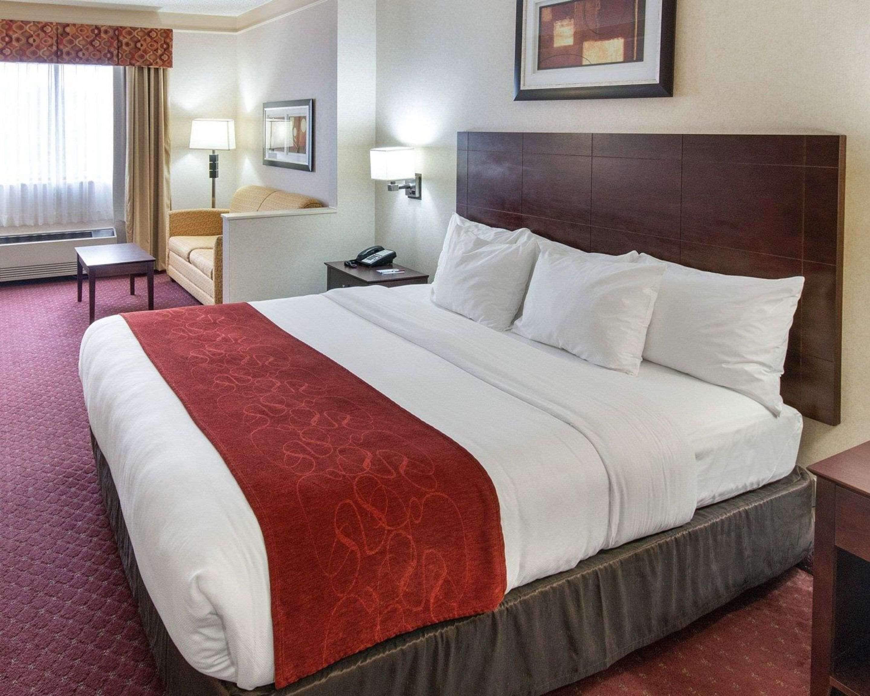 Habitación de hotel con una cama grande, una mesita de noche, una silla, un escritorio y una lámpara.