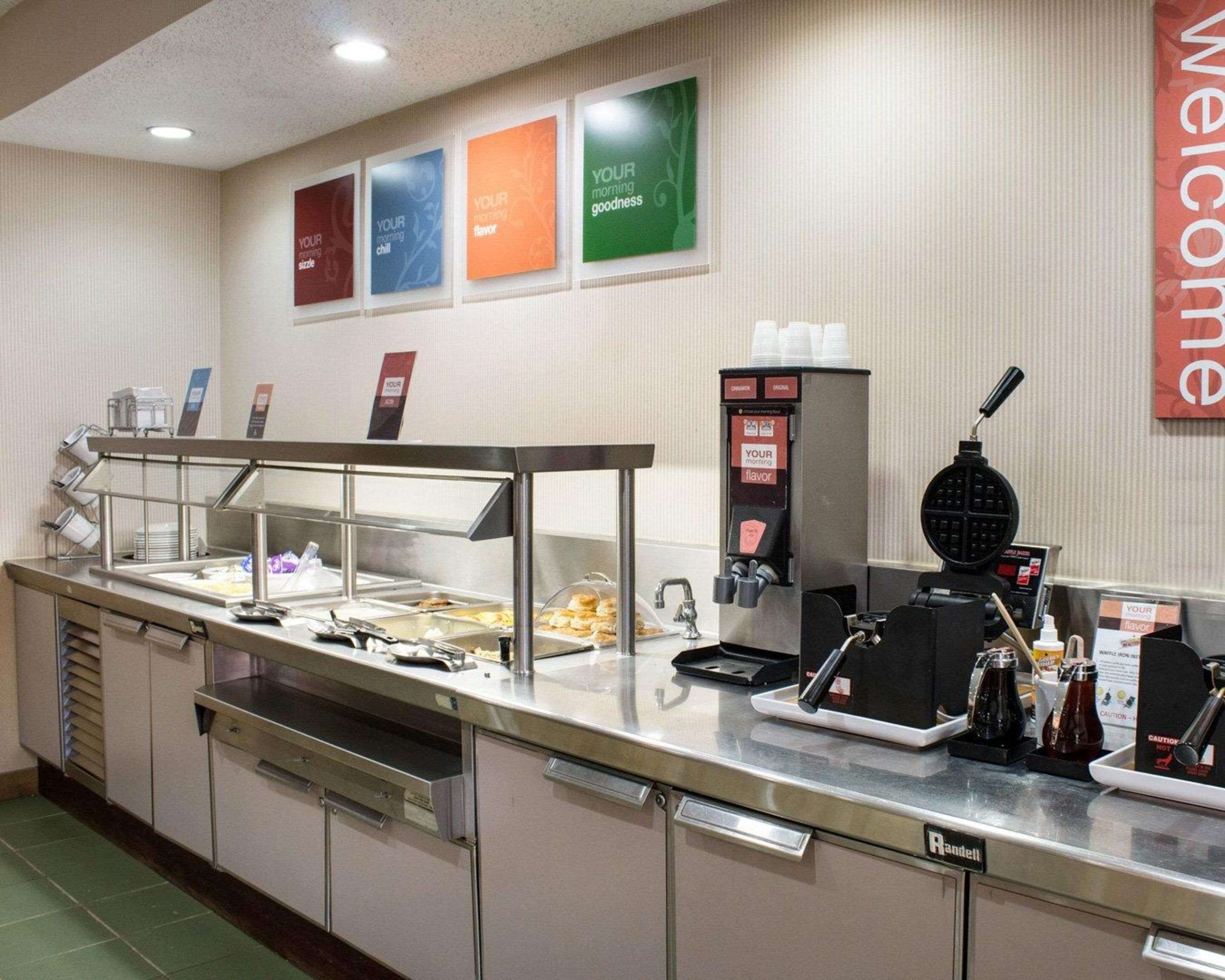 A buffet area with a self-service station, a coffee machine, and a welcome sign.
