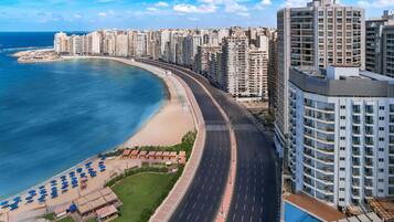 Un paisaje urbano costero con rascacielos, una playa y una carretera que serpentea a lo largo de la costa.