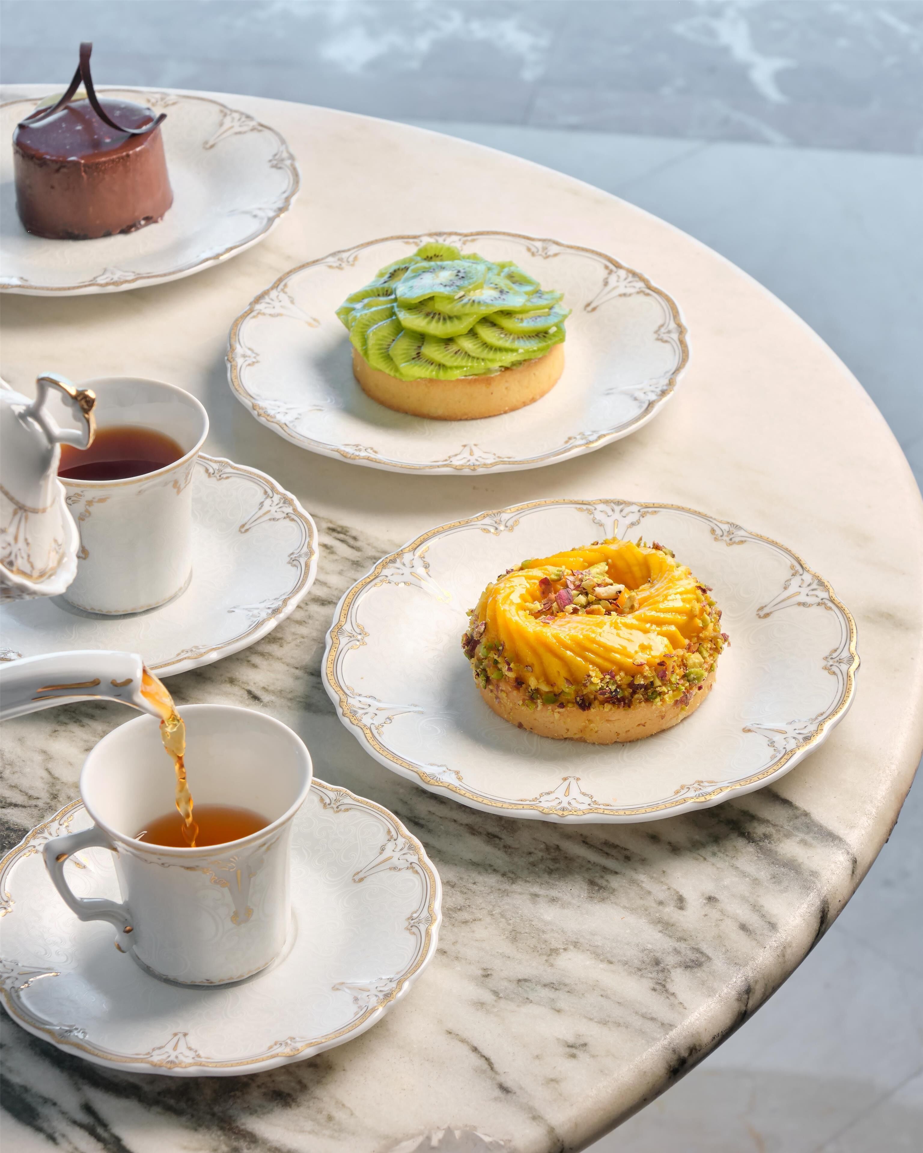 A table with a dessert, a teapot, and a cup of tea.