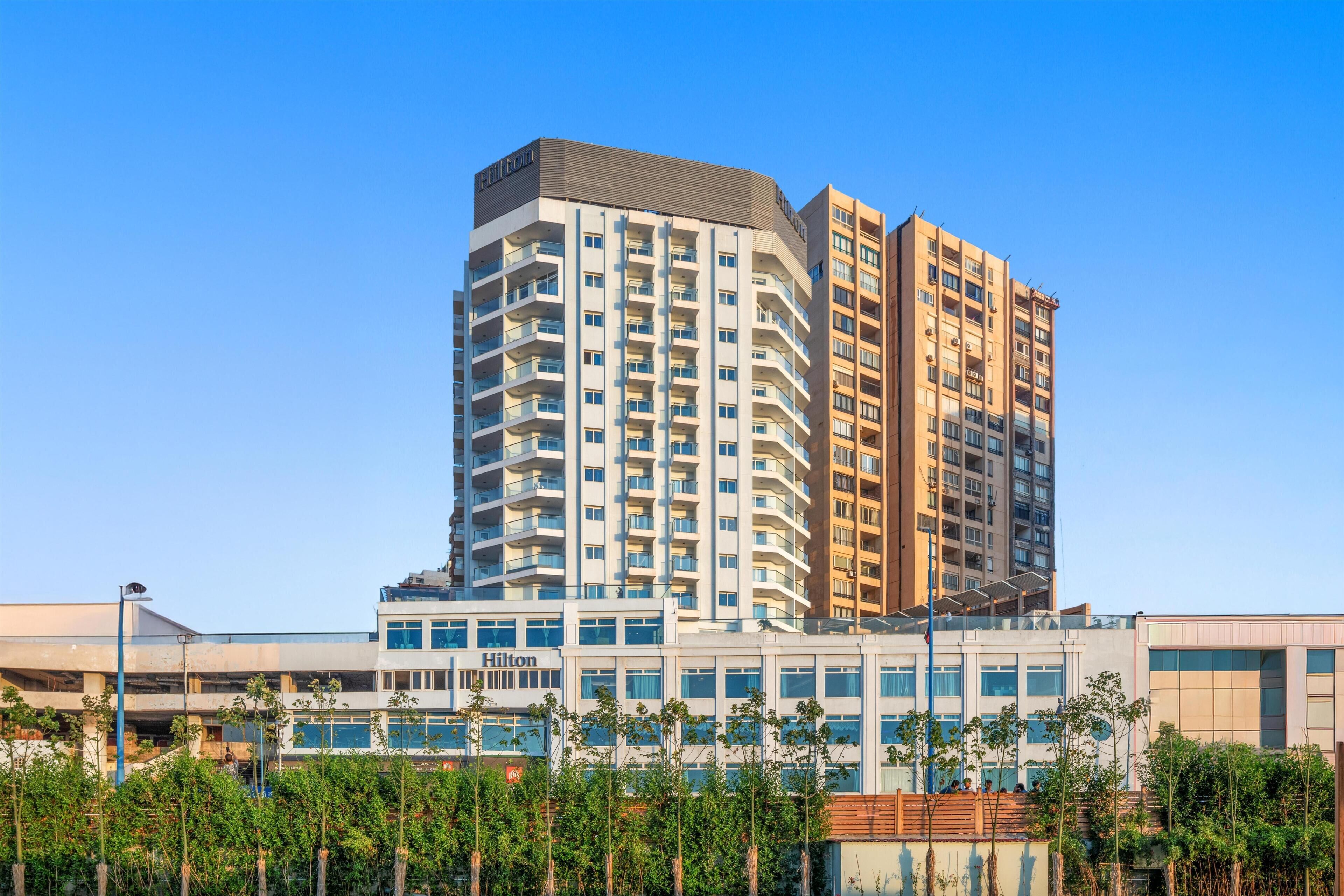 Un edificio de hotel de varios pisos con un diseño moderno, destacando un letrero de Hilton.