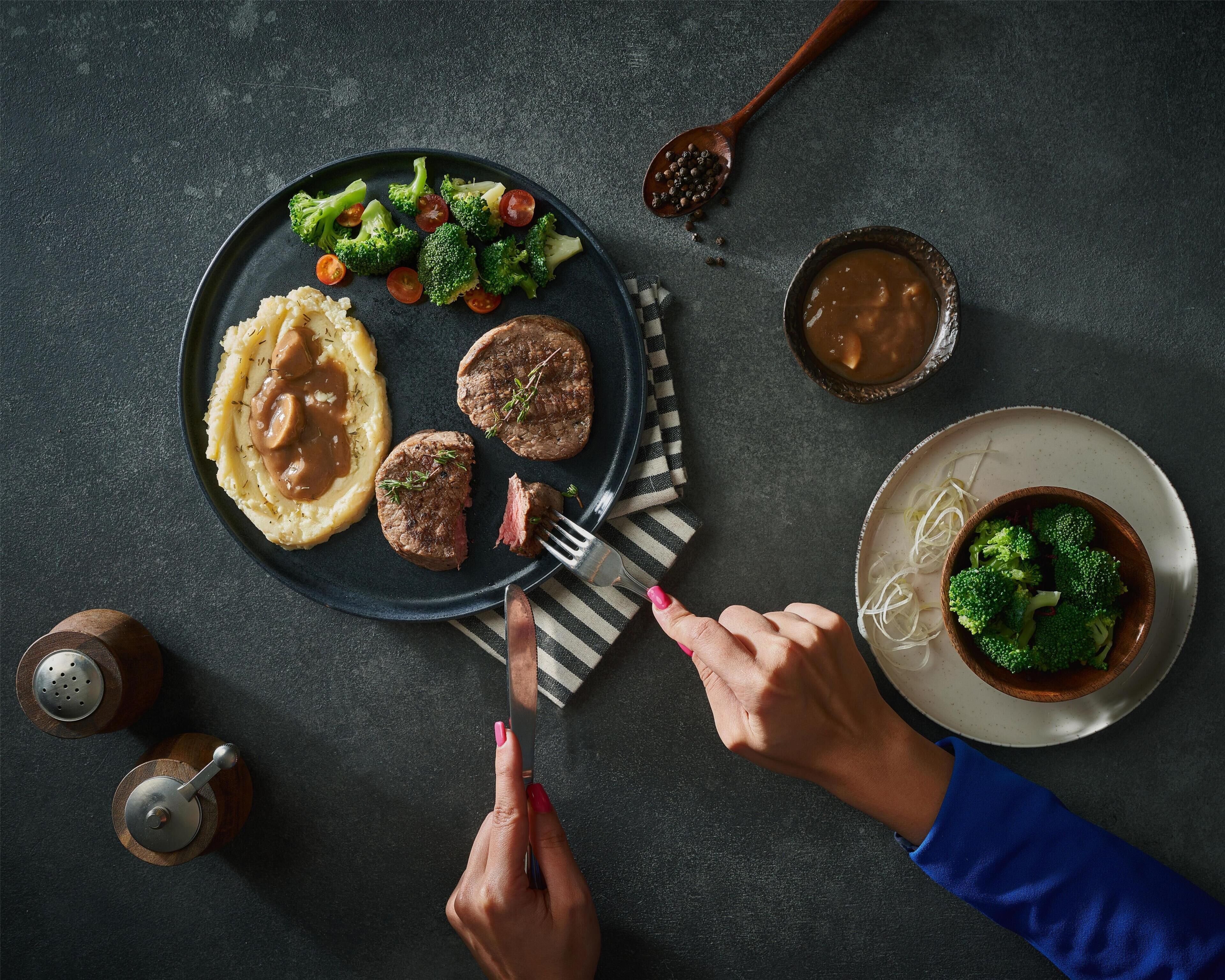 A dining table with a plate of food, a bowl of soup, and a spoon.