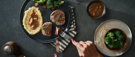 A dining table with a plate of food, a bowl of soup, and a spoon.