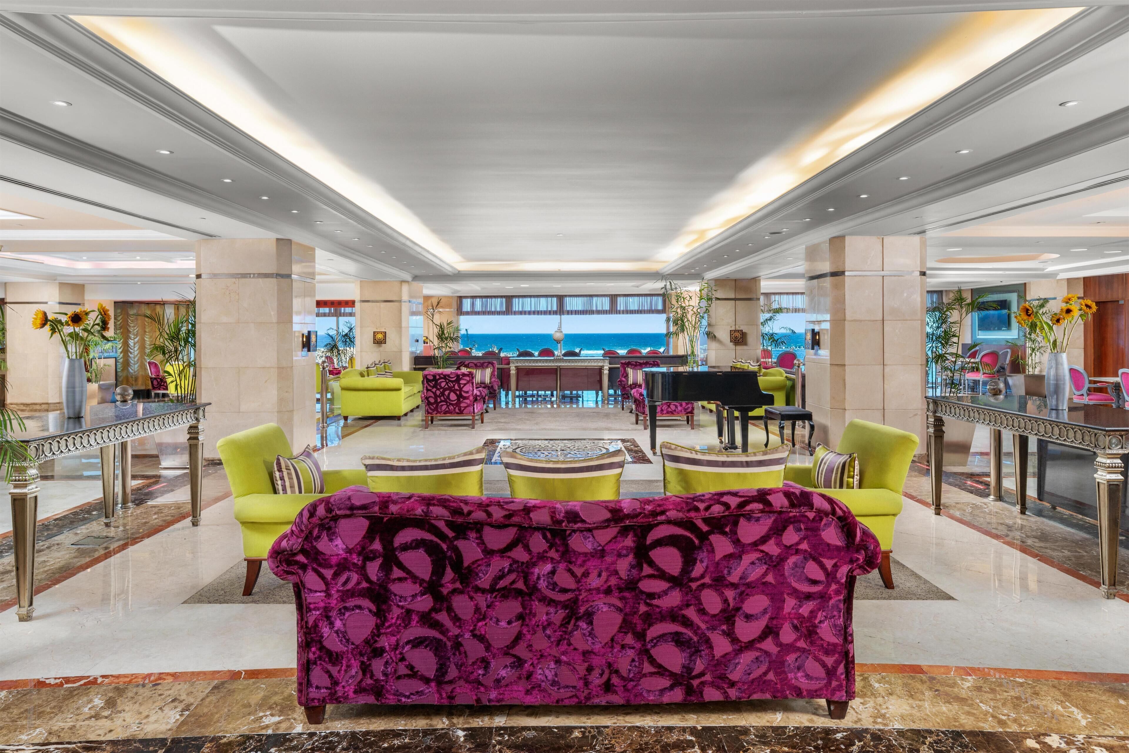 A spacious lobby with a central seating area, a view of the sea, and a modern design.