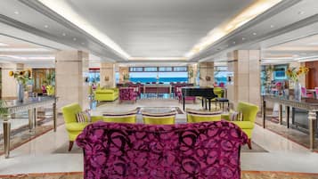 A spacious lobby with a central seating area, a view of the sea, and a modern design.