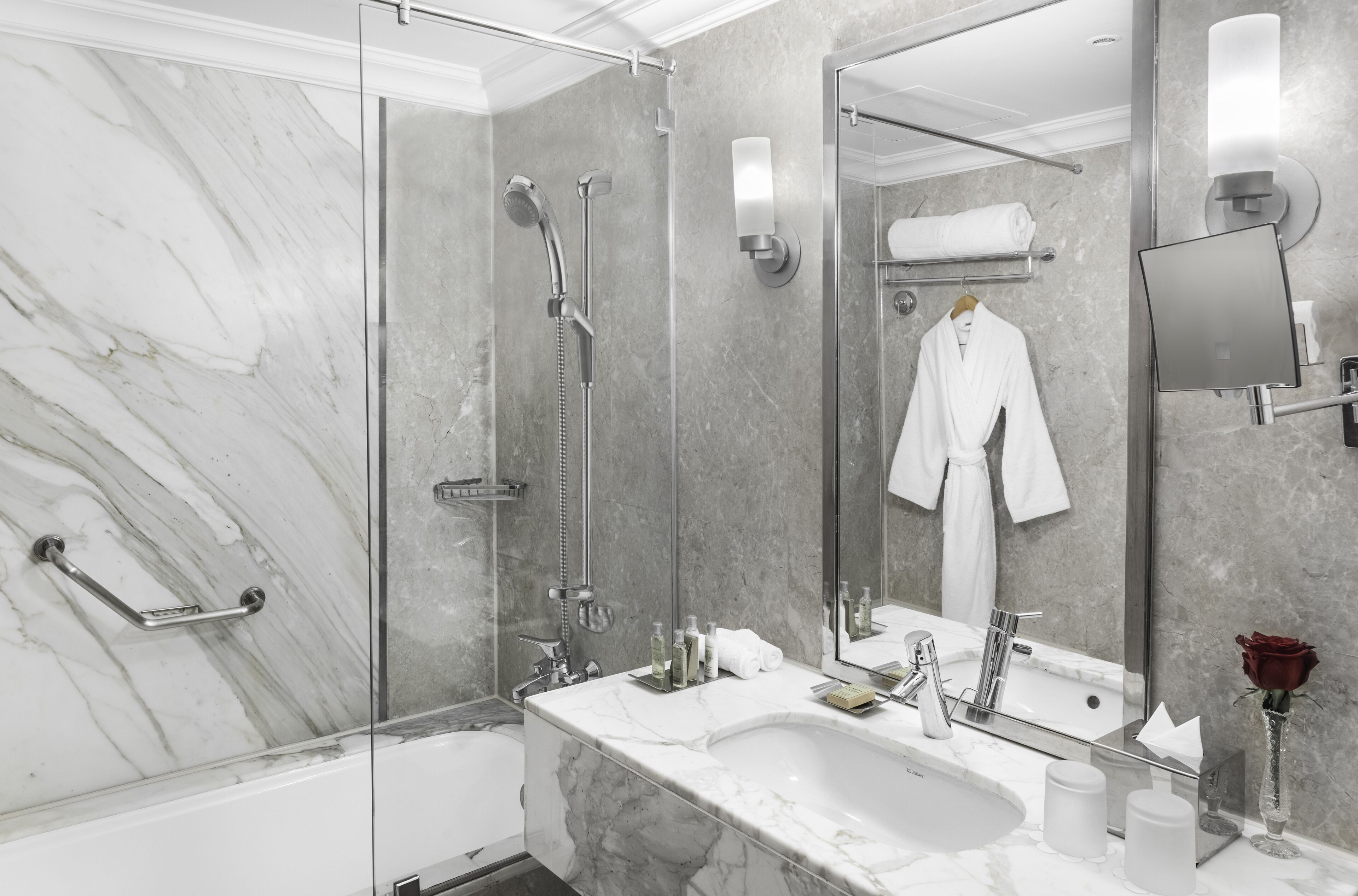 A modern bathroom with a glass-enclosed shower, a marble sink, and a large mirror.