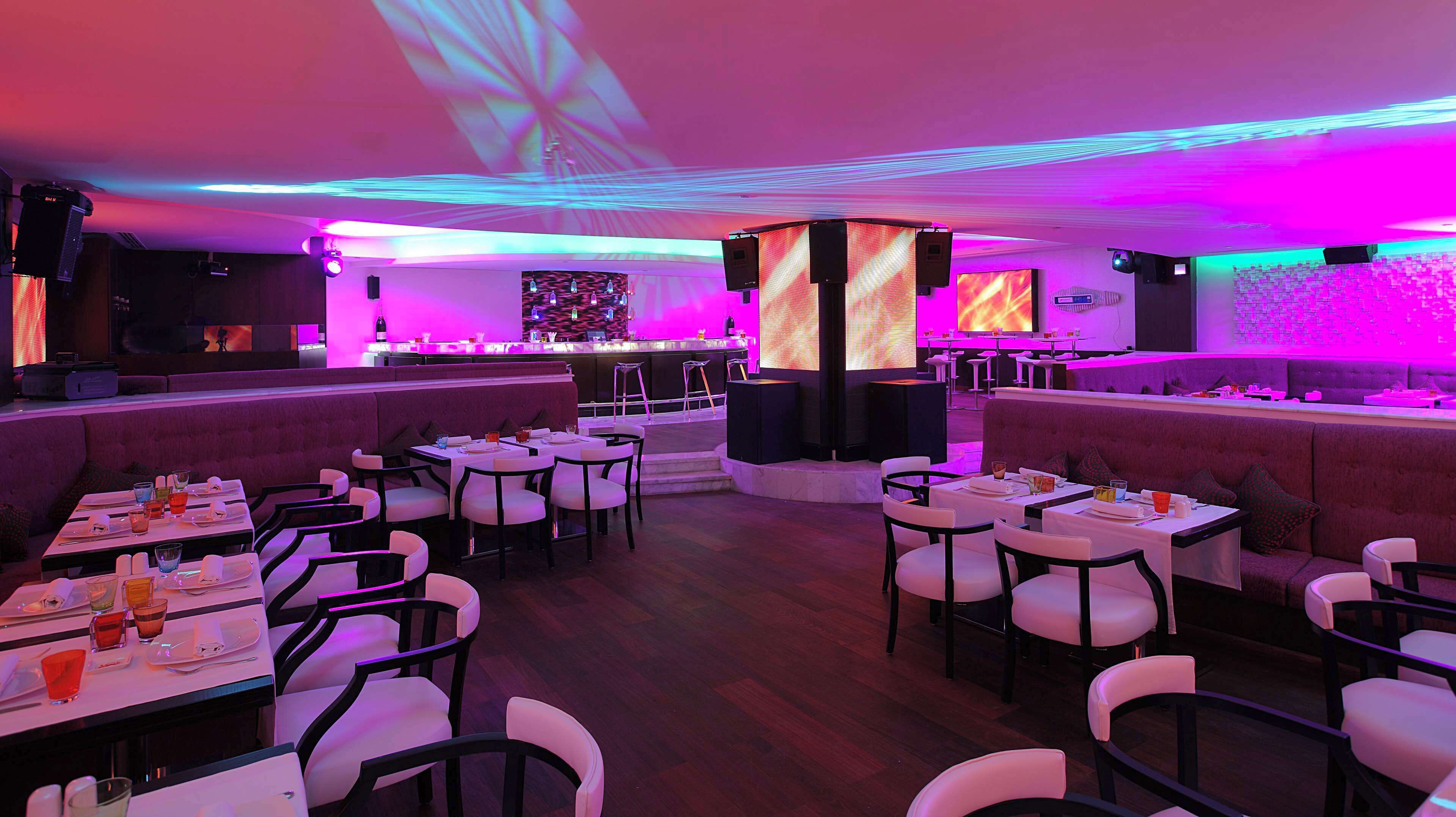 Een modern restaurant met een bar, zitplaatsen in boxen en aan tafels.