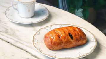 Een marmeren tafel met een croissant en een kop koffie op een schoteltje.