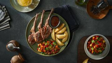 A plate with lamb chops, roasted potatoes, and a vegetable medley.