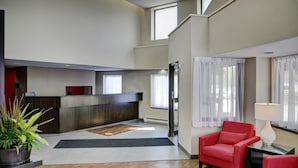 Un moderno vestíbulo de hotel con una recepción, área de descanso y grandes ventanales.