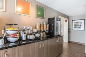 A modern kitchen with a black countertop, stainless steel appliances, and a variety of food containers.
