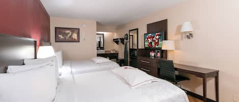 A hotel room with two beds, a desk, a chair, a television, and a mirror.