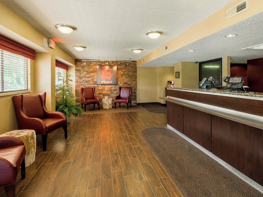 A reception area with a wooden floor, leather chairs, a stone wall, and a reception desk with a computer and phone.