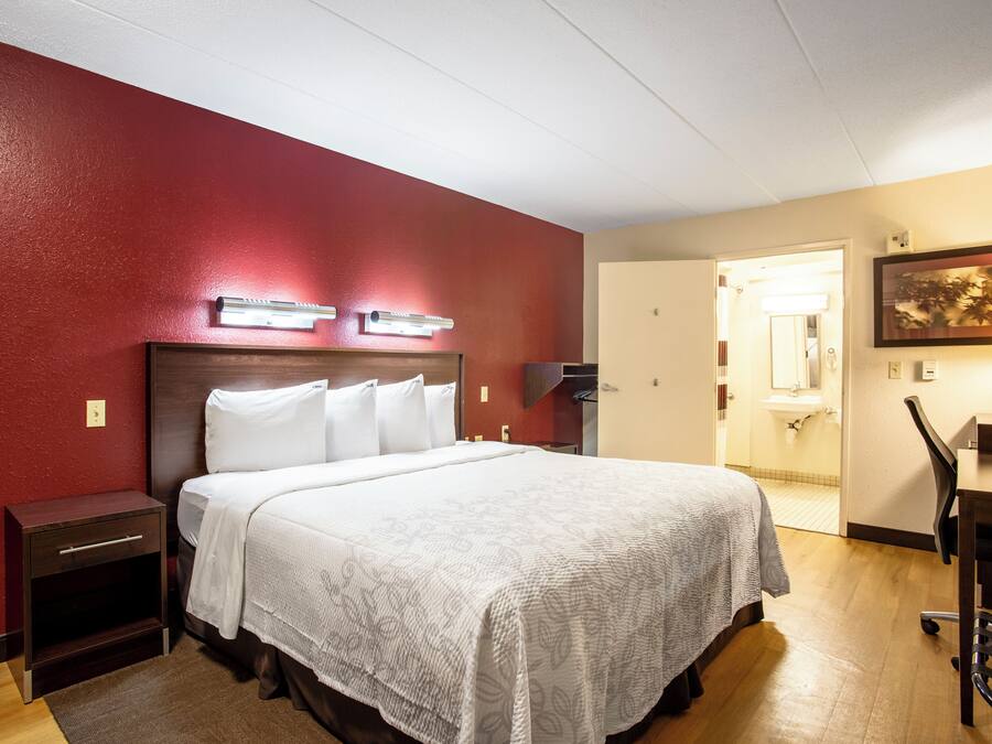 A hotel room with a bed, bedside tables, a desk, and a chair.