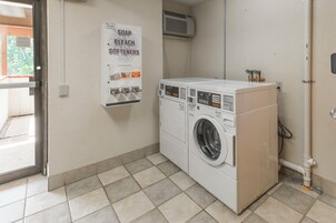 Un cuarto de lavandería con una lavadora y un cartel que enumera jabón, lejía y suavizantes.